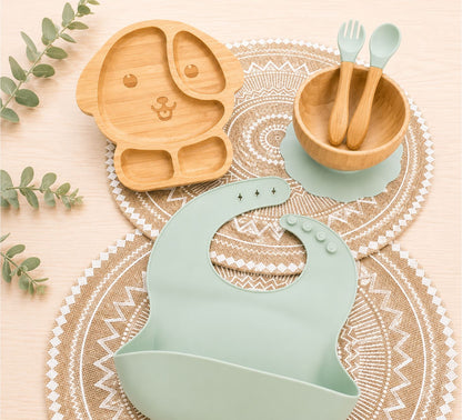 Organic bamboo dog-shaped baby feeding set, eco-friendly ,silicone bib, suction bowl, and wooden spoon and fork in light green colour.